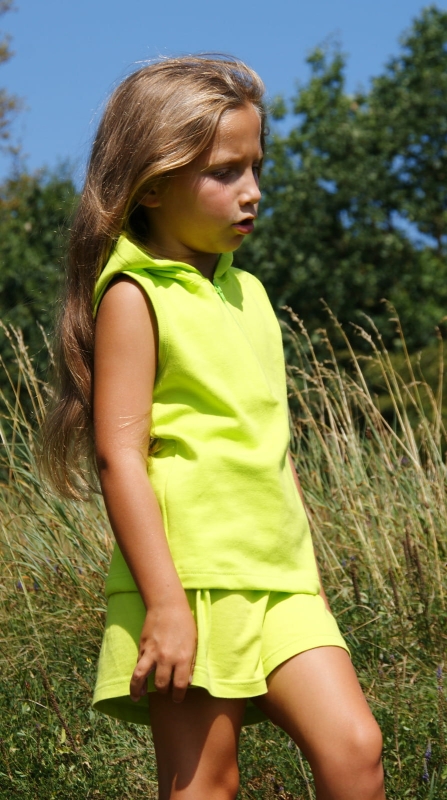 Dziewczynka w koszulce bez rękawków, z kapturem, zapinana na zamek 1/3 długości, bawełniana w kolorze jasnej soczystej zielni, fason VKD-4, pięknie komponuje się z bawełniana krótką spódniczką w jasno zielonym kolorze.JPG