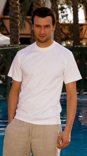 Model w klasycznym białym t-shircie, koszulka z krótkim rękawem, fason VKT-1, zwykłe wszycie rękawów, wykończenie pod szyją delikatnym ściągaczem, w stylizacji z beżowymi spodniami .jpg