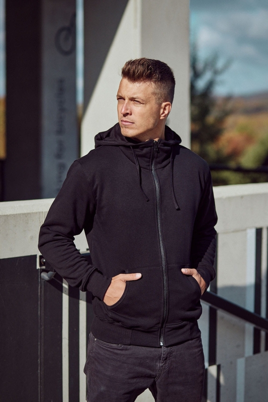 Model od boku w czarnej bluzie dresowej rozpinanej z kapturem fason VBL-36, bluza bawełniana, stójka, kieszeń typu kangurka, rękawy zakończone ściągaczem, dół bluzy wykończony ściągaczem.jpg