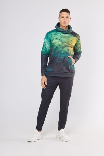 Model w bluzie dresowej fason VBL-46, bluza nierozpinana z kapturem, kieszeń typu kangurka, grafika sportowa nr 4001, tło tonalna zieleń z czarną siatką, w stylizacji z długimi sportowymi czarnymi spodniami.jpg