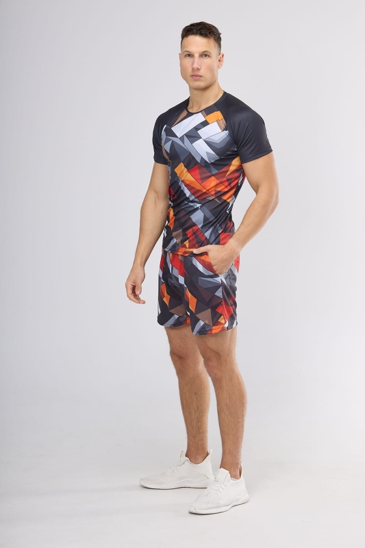 Model w koszulce sportowej fason VKT-70-sub, z grafiką 4000, krótki rękaw z raglanowym wszyciem, rękawy czarne, korpus koszulki z geometrycznym wzorem w odcieniach pomarańczu i szarości, w stylizacji z krótkimi spodenkami z tą samą grafiką.jpg