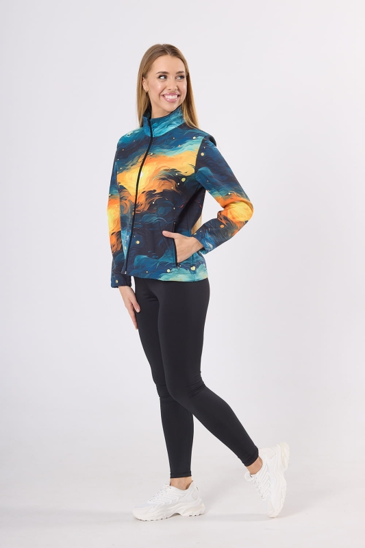 Modelka od boku w kurtce softshell fason VSOFTD-98 z grafiką 4004 w stylizacji z czarnymi leginsami, kurtka delikatnie taliowana, zamek główny, dwie kieszenie z zamkami, nadruk pociągnięcia pędzla w barwach granatowy, pomarańczowy, żółty.jpg