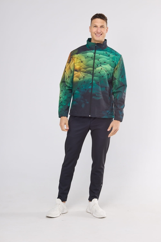 Model w Softshellu fason VSOFTM-98 grafika 4001 w stylizacji z czarnymi spodniami sportowymi, softshell rozpinany ze stójką, dwie kieszenie zapinane na zamek, kolorystyka tonalna od ciemnej do jaśniejszej zieleni, z geometryczną siatką.jpg