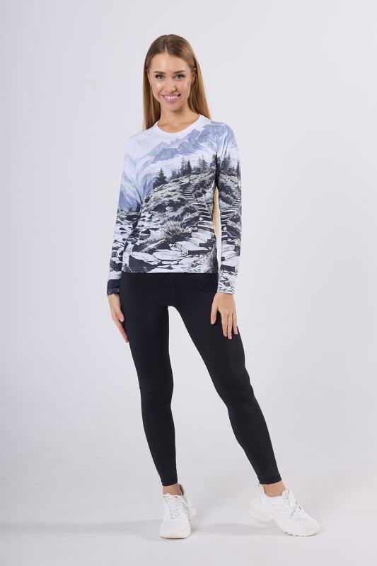 Modelka w stylizacji longsleeve fason VKDRd-102 grafika Mountains 0055 z czarnymi leginsami, koszulka krój dopasowany, przedstawiający górską scenerię, w kolorystyce dominują odcienie bieli, szarości, czerni i delikatnego błękitu.jpg