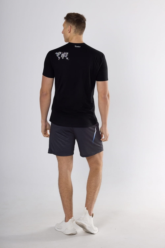 Model stojący tyłem w koszulce męskiej fason VKT-1-sub z krótkim rękawem, czarna, na ramieniu zarys mapy świata.jpg