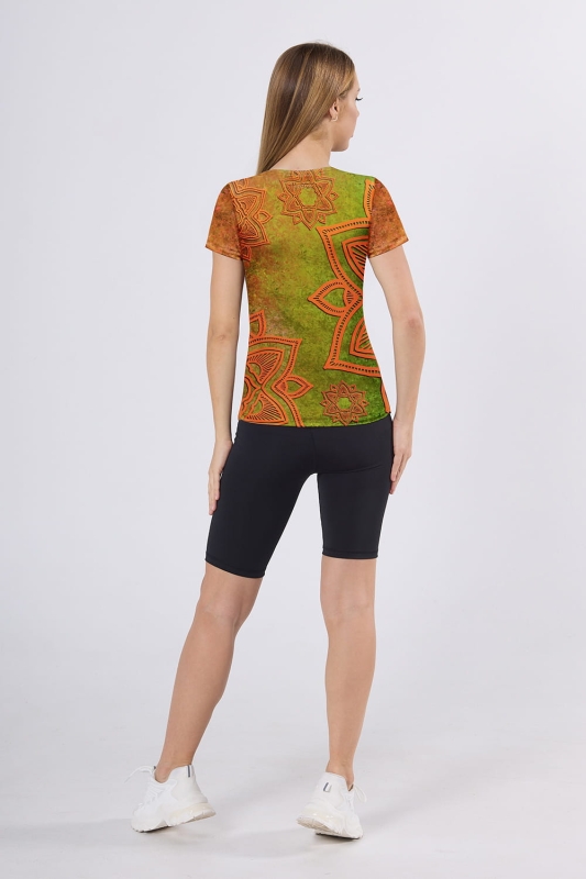 Modelka stojąca tyłem w sportowym stroju, koszulka w pomarańczowych odcieniach grafika Mandala 0096, fason VKD-2, w stylizacji z czarnymi sportowymi leginsami krój przed kolanko.jpg