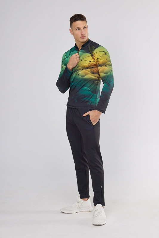 Mężczyzna stojący bokiem w koszulce sportowej z długim rękawem - longsleeve fason VKDRm-104 ZIP, zamek 1/3, delikatna stójka, długi rękaw, w barwach zieleni i żółtego z delikatną czarną siatką, nowoczesna sportowa grafika Ventus.jpg