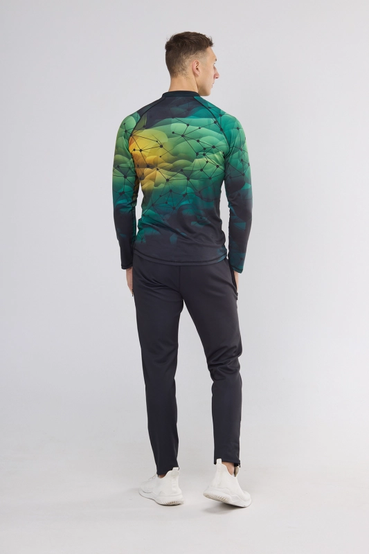 Mężczyzna stojący tyłem w longsleeve fason VKDRm-104 ZIP, delikatna stójka, długi rękaw, w barwach zieleni i żółtego z delikatną czarną siatką, w stylizacji z czarnymi sportowymi spodniami, nowoczesna sportowa grafika Ventus.jpg