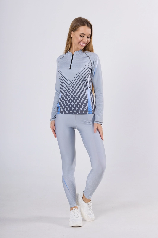 Modelka w longsleevie sportowym fason VKDRd-104 zapinanym na zamek 1/3, z delikatną stójką, raglanowe wszycie rękawów, koszulka delikatnie taliowana, w barwy jasno szare z geometrycznymi delikatnymi akcentami, grafika Sport szary 4009 Ventus.jpg