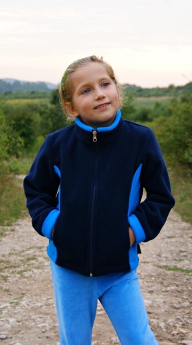 Polar dzieciecy fason unisex VPL-12 w kolorze granatowy z niebieskimi wstawkami po bokach, zapinany na zamek, stójka, bez kaptura, dwie kieszenie po bokach, polar zaprezentowany na dziewczynce ale jest to fason unisex również dla chłopca.jpg