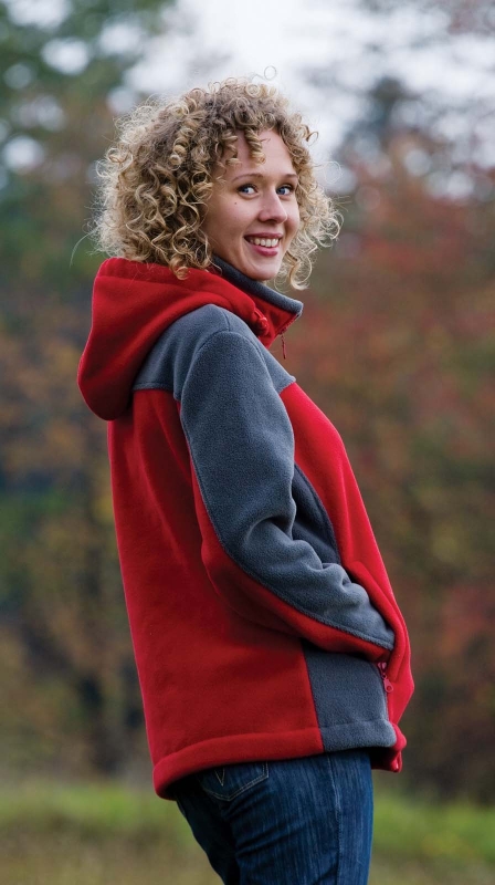 Zbliżenie na modelkę w polarze od boku, fason VPL-10, kolor polaru czerwono-szary, szare wstawki po bokach, na karku i rękawach, dopinany kaptur, stójka, polar zapinany na zamek, dwie kieszenie zapinane na zamek.jpg