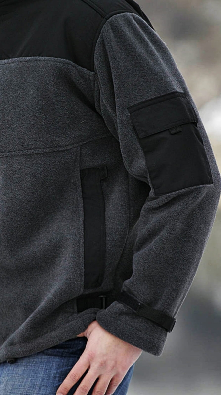 Zbliżenie na rękaw polaru fason VPL-11 Ventus prezentowany na modelu,  kolor ciemnomelanżowy, czarna kieszeń z oratlionu na lewym rękawie, ściagający pas parciany czarny przy rękawie.jpg