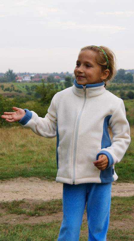 Polar dzieciecy fason unisex VPL-12 w kolorze ecru z wstawkami po bokach w kolorze lotnik, zapinany na zamek, stójka, bez kaptura, dwie kieszenie po bokach, polar zaprezentowany na dziewczynce.jpg