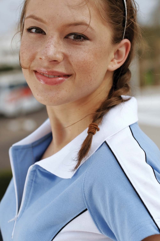 Zbliżenie na modelkę i wykończenia koszulki polo fason VKPd-9, biały kołnierzyk, koszulka zapinana na zamek, niebieska z białymi wstawkami i wypustką.jpg