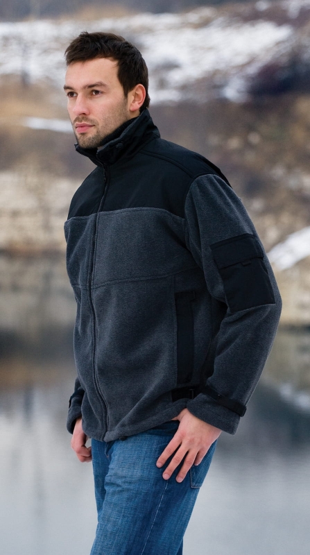 Model bokiem w polarze fason VPL-11 w kolorze ciemny melanż, czarne wstawki z ortalionu na ramionach, stójce, czarna kieszeń na lewym rękawie, główny zamek, dwie kieszenie na zamek, ściągające czarne pasy parciane przy rękawach i po bokach polaru .jpg