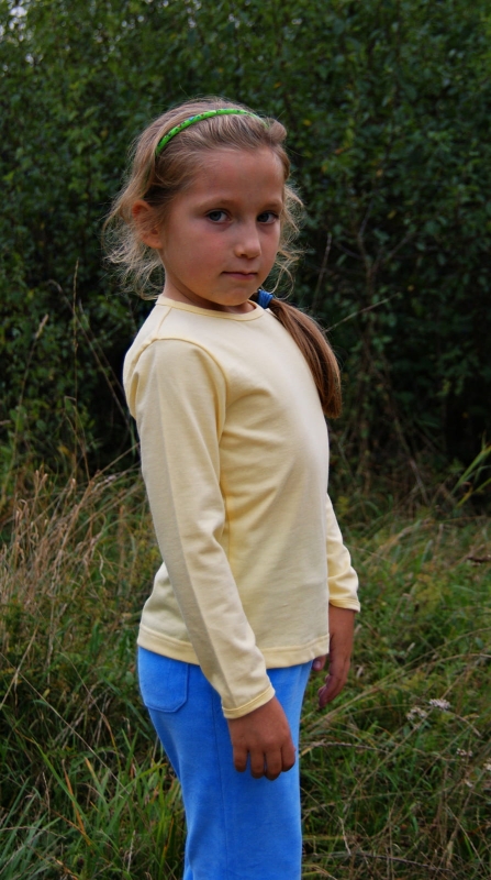 Dziewczyna w koszulce dziecięcej z długim rękawem w kolorze brzoskwiniowym fason VKDRd-1, pod szyja lamówka, koszulka bawełniana.jpg