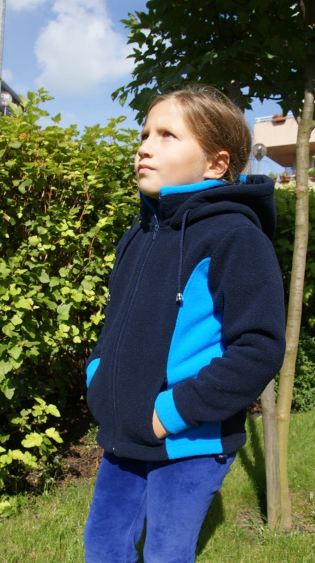 Polar dziecięcy fason unisex  VPL-30 w kolorze granatowym z niebieskimi wstawkami po bokach,  zaprezenowany na dziewczynce, ale jest to fason unisex więc również dla chłopców, doszyty kaptur, stójka, polar zapinany na zamek, dwie kieszenie po bokach,.jpg